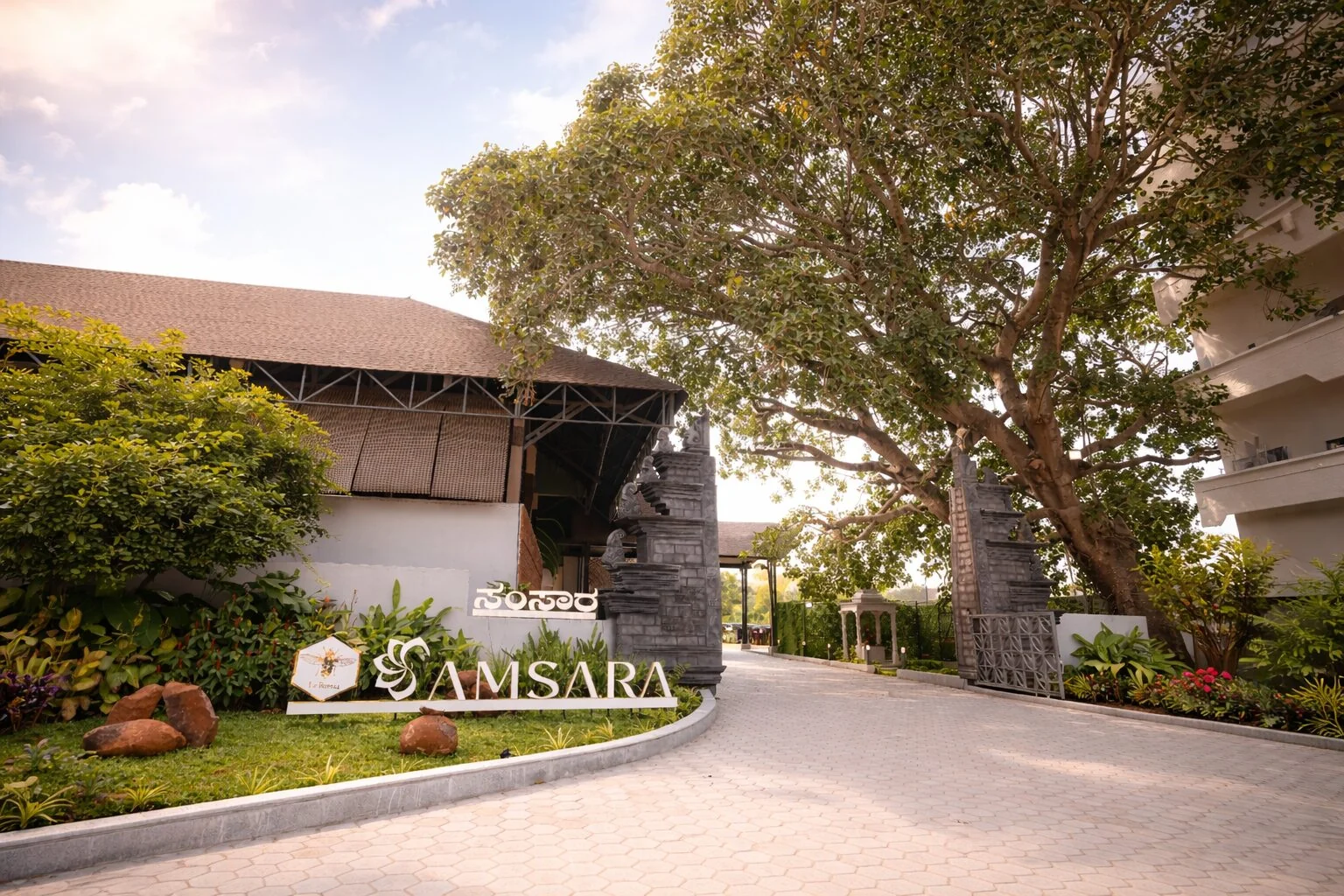 Samsara’s stone entrance gateway and signage beneath a spreading tree