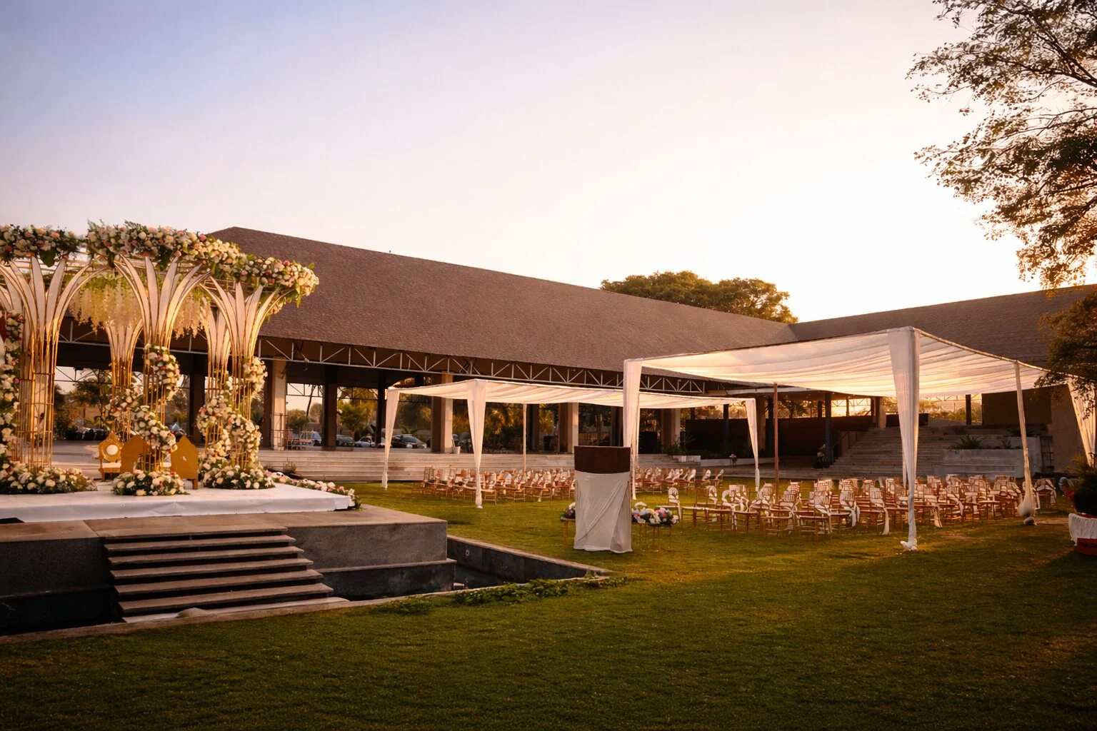 A ceremony setup on Padma Lawns with white canopies and a floral mandap at sunset