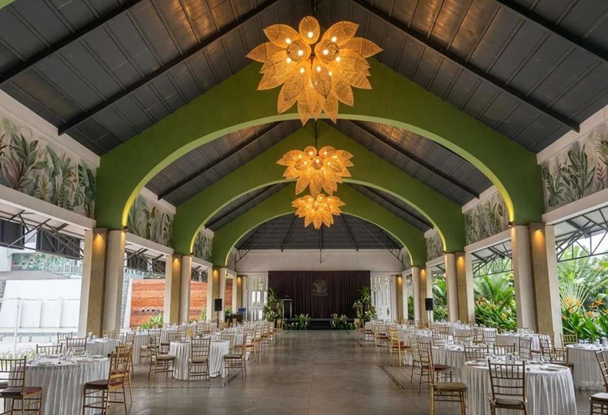 Padma Pavilion set with round dining tables beneath green arches and lotus lamps