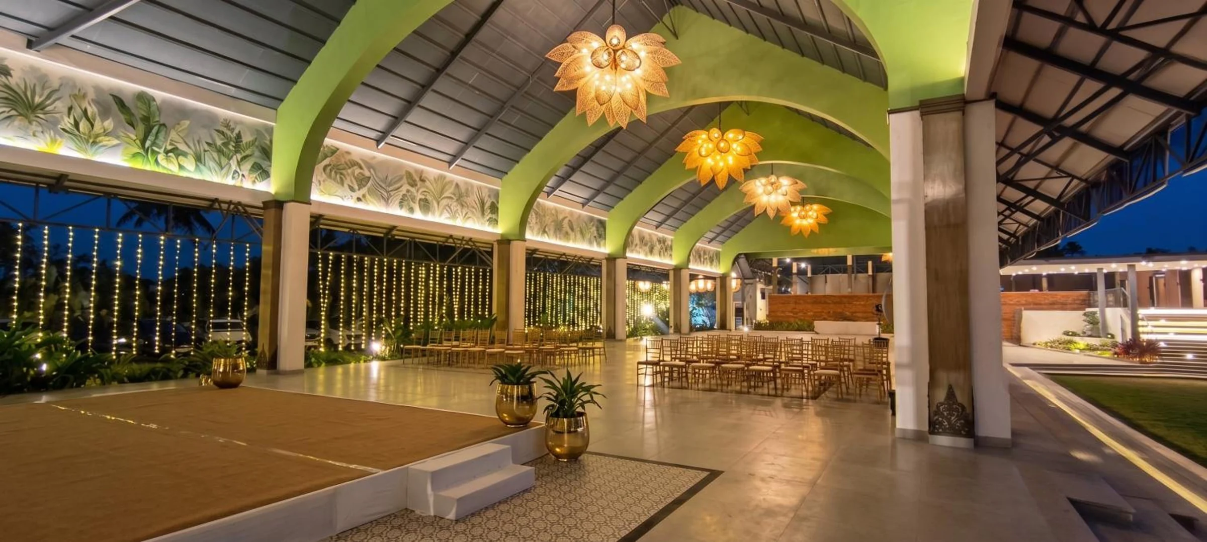 Padma Pavilion at night with warm lotus lamps, a low stage and rows of chairs