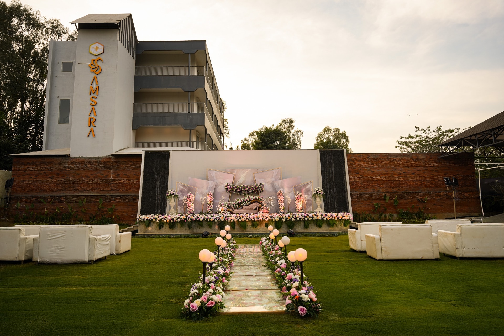 Grand reception with LED screen stage and floral aisle at dusk