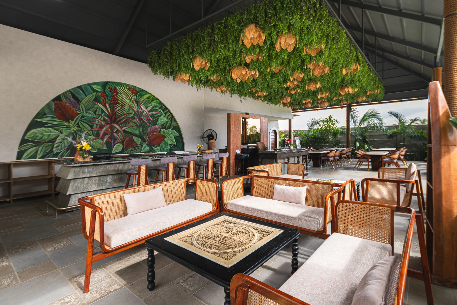 Daylight in the reception lounge, with cane sofas and the botanical mural