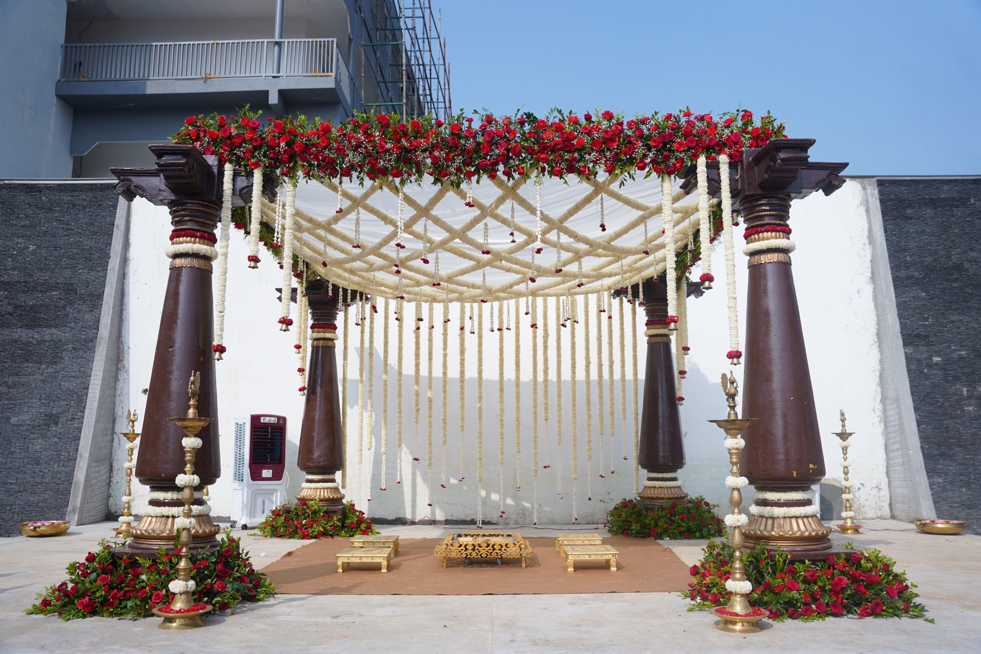 Traditional South Indian wedding mandap with carved pillars and red roses