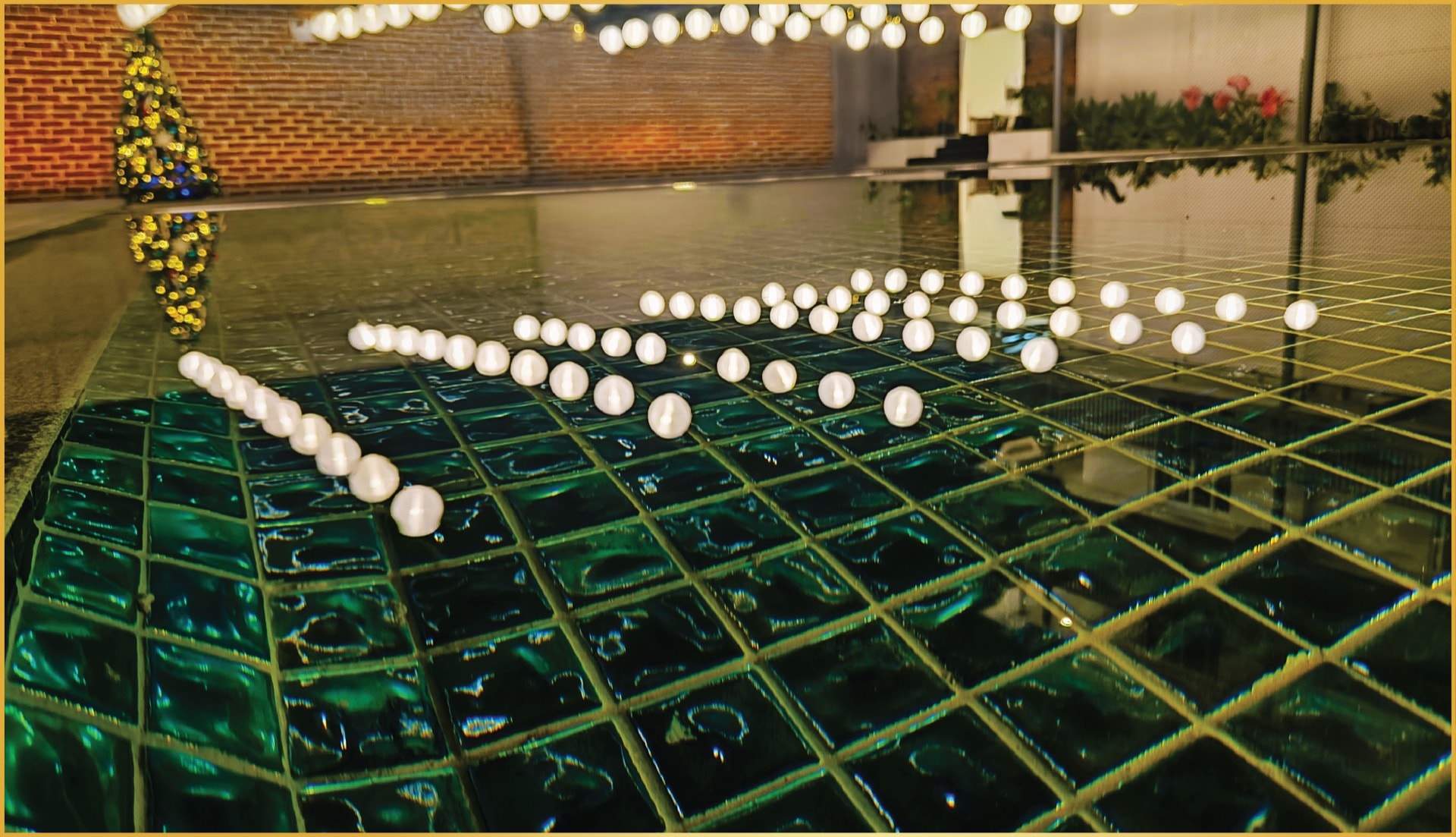 Swimming pool at night with floating light orbs and green mosaic tiles