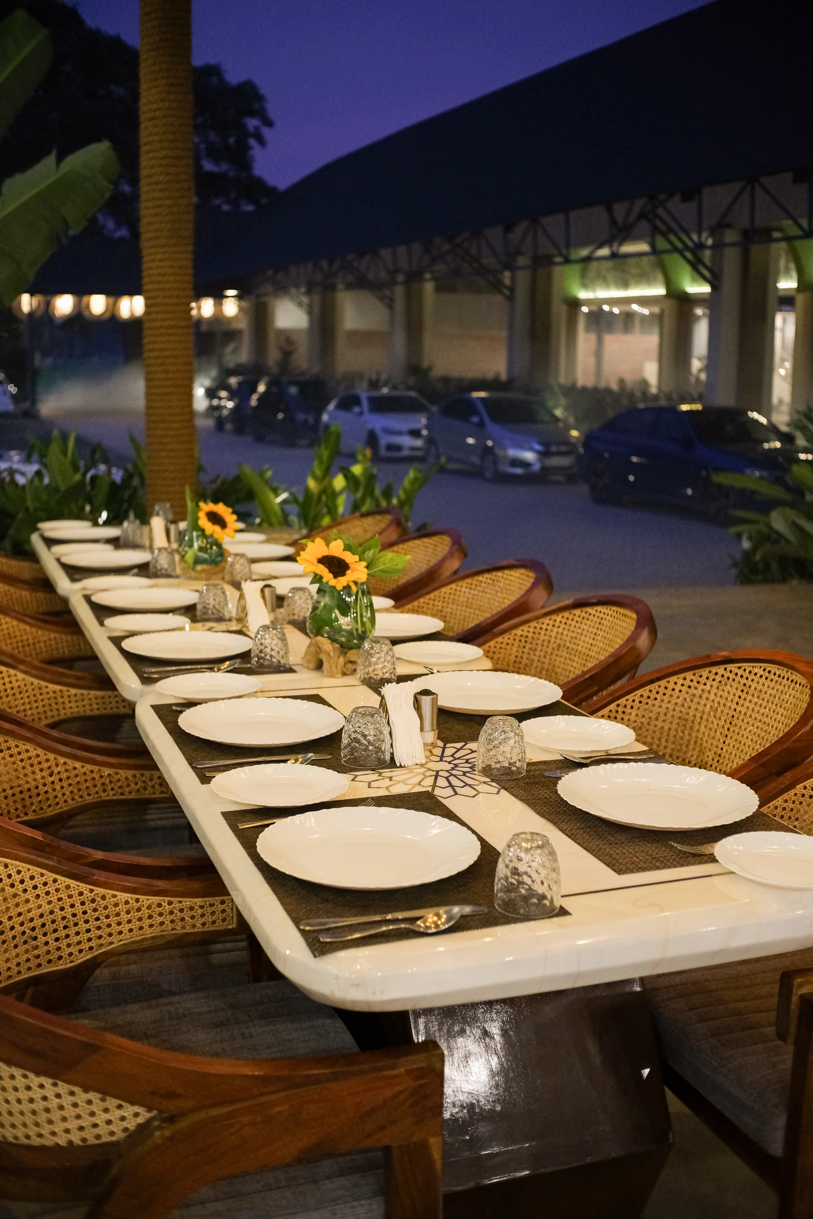 Dinner place settings and cane chairs beside the restaurant’s open courtyard at dusk