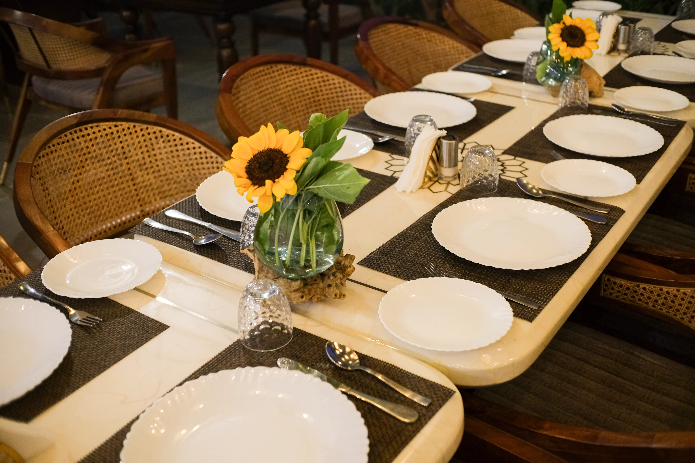 Sunflowers, white plates and glassware on a restaurant table set for dinner