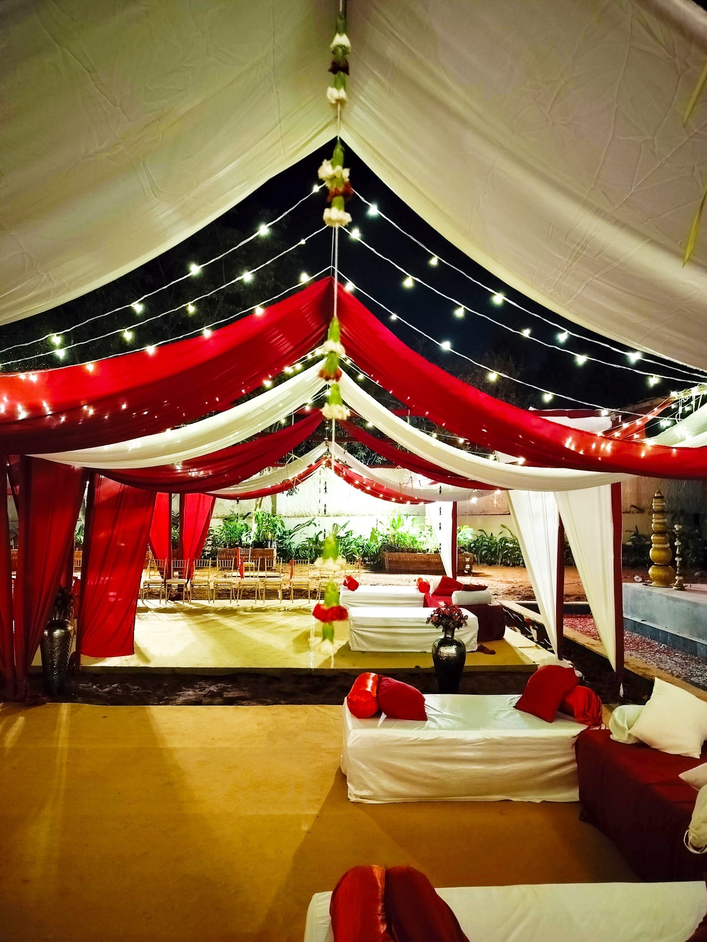 Red and white shamiana tent with fairy lights and lounge seating