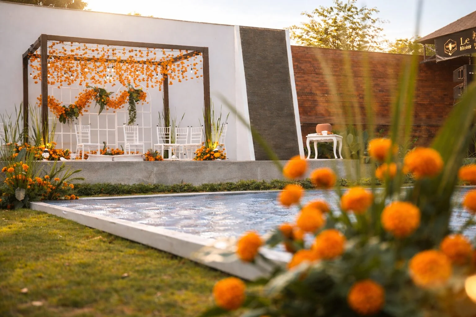 Marigold flowers beside the ceremonial water feature and a white-and-orange mandap
